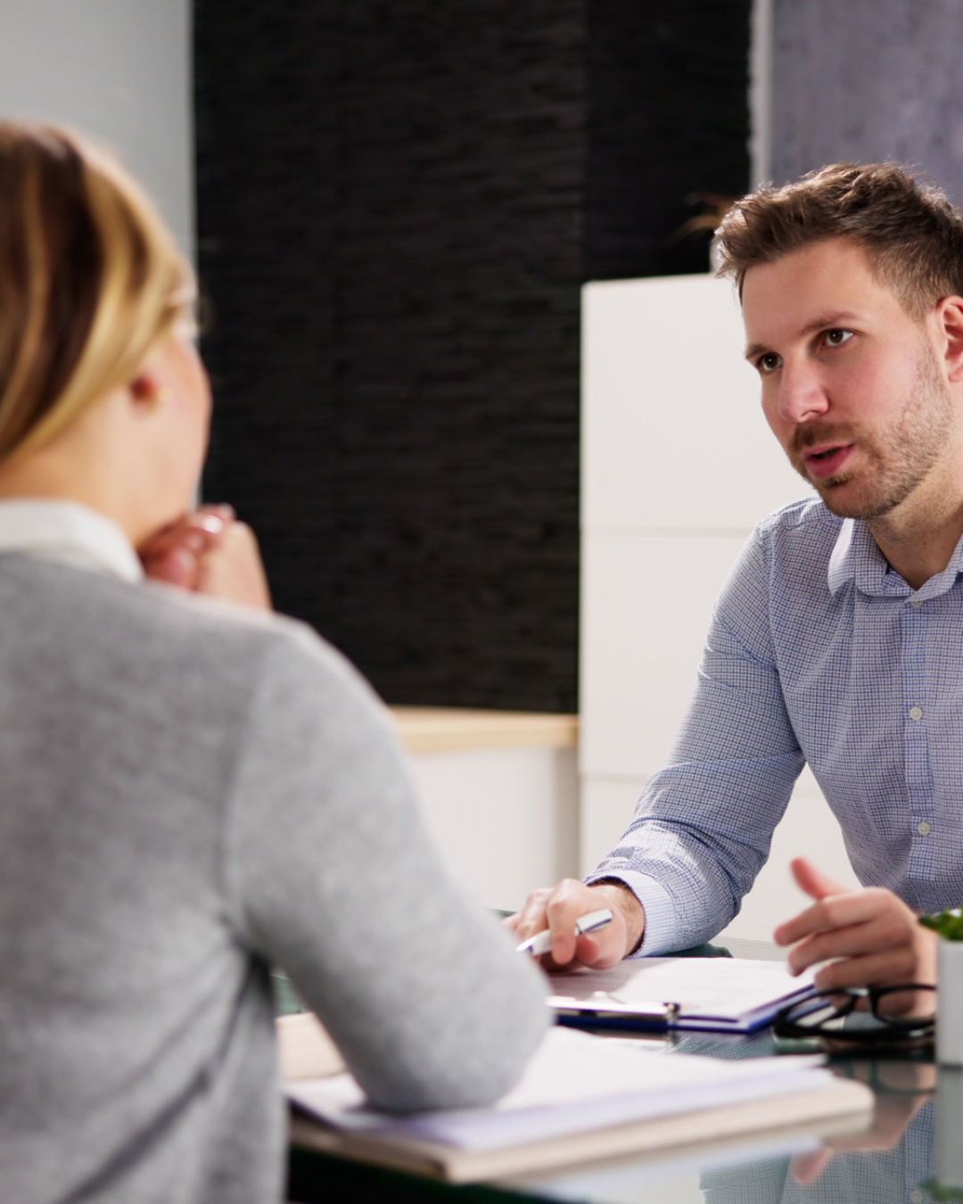 Man and woman discussing paperwork across an office desk